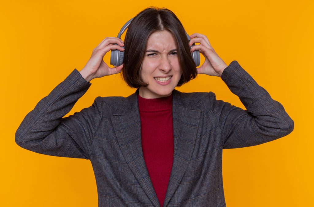 young woman with short hair wearing grey jacket with headphones